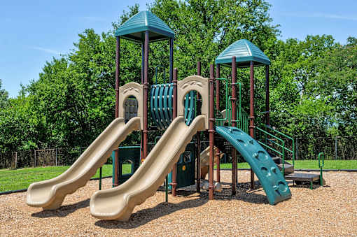 A playground with a green slide and brown slide.