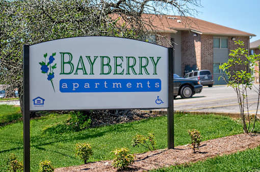 A sign for Bayberry Apartments is shown in front of a building.