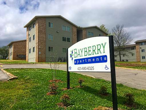 A sign for Bayberry Apartments stands in front of a building.