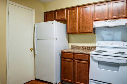 A white refrigerator stands next to a stove in a kitchen.