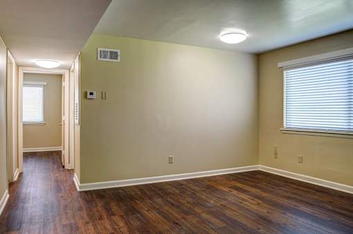 A room with wooden floors and a window with blinds.