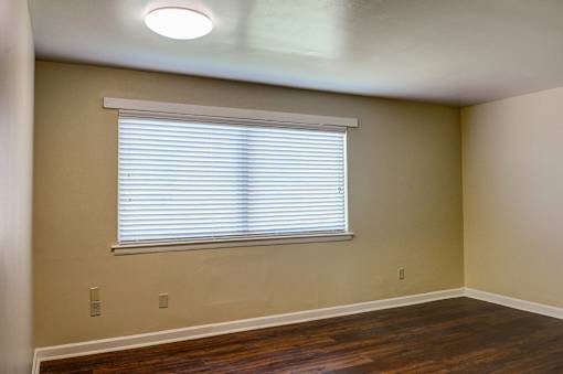 A room with a window covered by white blinds.