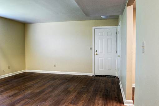 A room with a white door and wooden floors.