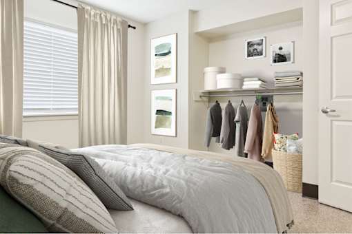 A bedroom with a bed, pillows, a shelf with clothes and towels, and pictures on the wall.