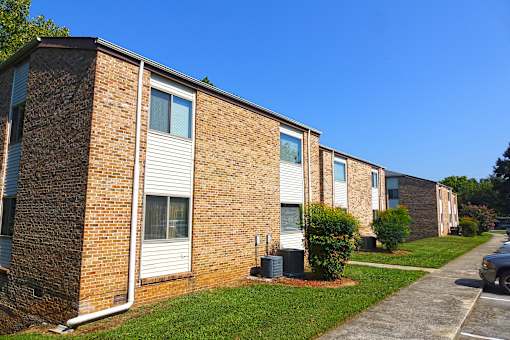 A row of brick apartment buildings with green bushes in front.