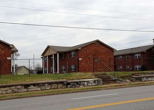 A row of red brick houses with a stone wall in front.
