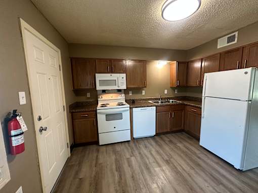 A kitchen with a white refrigerator, white oven, and white dishwasher.