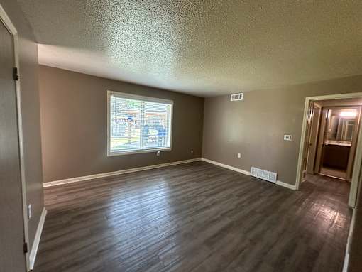 A room with a window and wooden flooring.