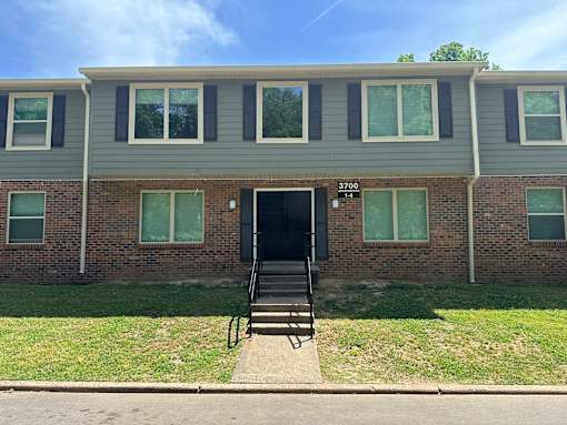 A brick building with a black door and windows with white frames.