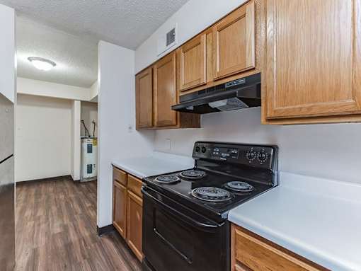 A kitchen with a black stove top oven and wooden cabinets.