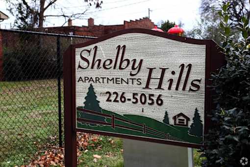 A sign for Shelby Hills Apartments with a phone number on it.