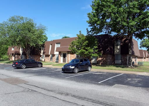 Two cars parked in a parking lot in front of a building.