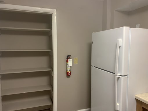 A white refrigerator is in a room with a white door and a white wall.