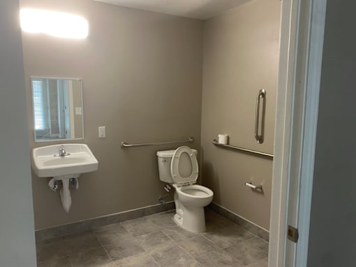 A bathroom with a toilet, sink, and mirror.