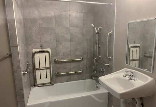 A white bathtub sits next to a white sink in a bathroom.