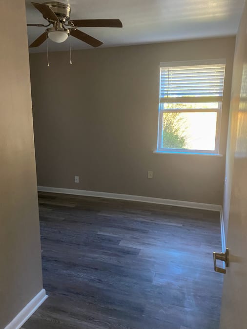 A room with a ceiling fan and a window with blinds.