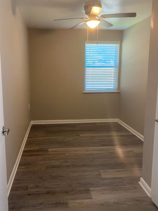 A room with a ceiling fan and a window with blinds.