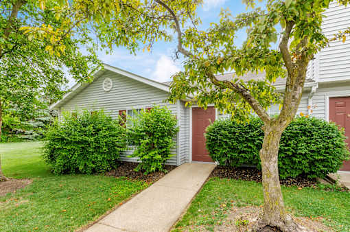 A house with a red door and a tree in front.