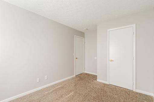 A room with two doors and carpeted floor.
