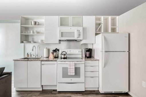 A white kitchen with a refrigerator, oven, and microwave.at Sky Central, Cincinnati, OH 45202