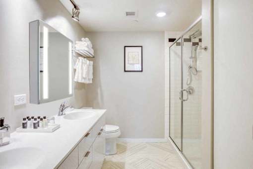 A white bathroom with a sink, mirror, toilet and shower.at Sky Central, Cincinnati, 45202