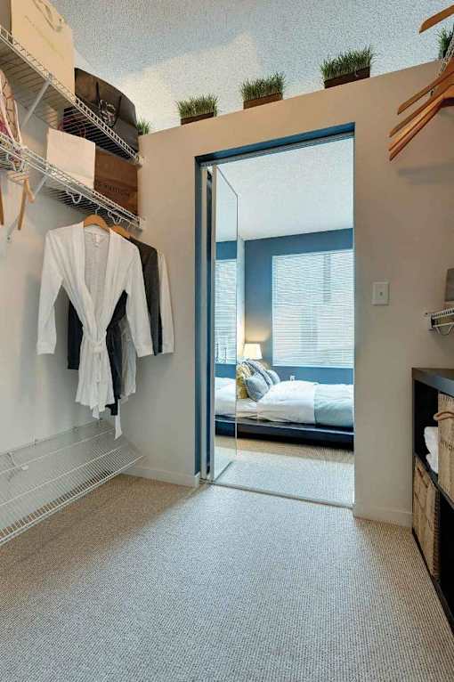 A bedroom with a bed, a window, and a closet with clothes hanging.at Sky Central, Ohio