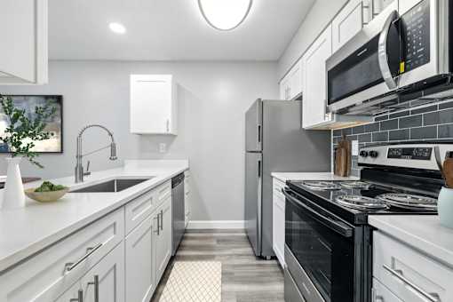 A modern kitchen with white cabinets and stainless steel appliances.at Hanna Village, Indianapolis, IN