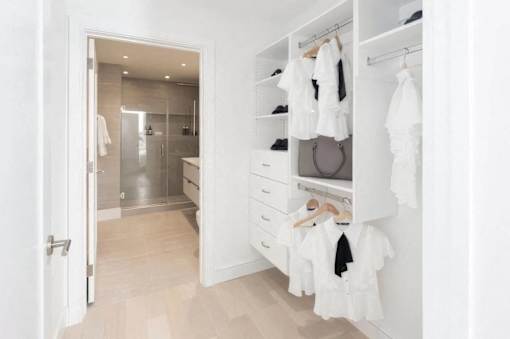 A white closet with clothes hanging and a bathroom in the background.at Sky Central, Cincinnati, OH