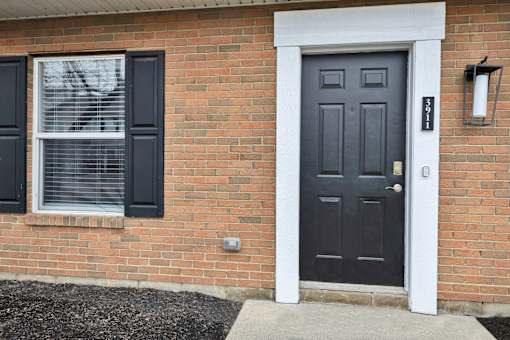 A black door with a white frame is on a brick house.