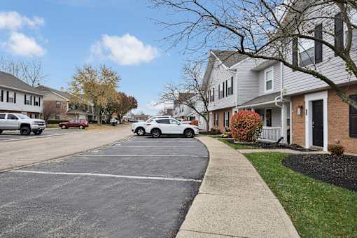 A white car is parked on the street in front of a house.