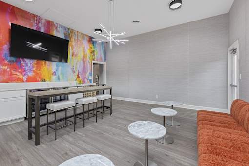a living room with a bar with stools and a television at Indian Lookout Apartments, West Carrollton, 45449