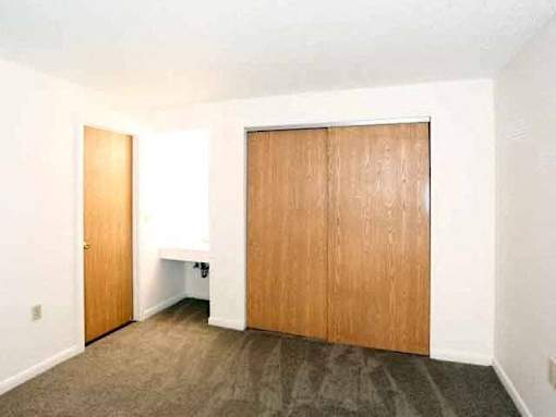A room with a carpeted floor and two wooden doors.