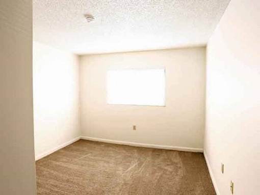 A room with a window and carpeted floor.