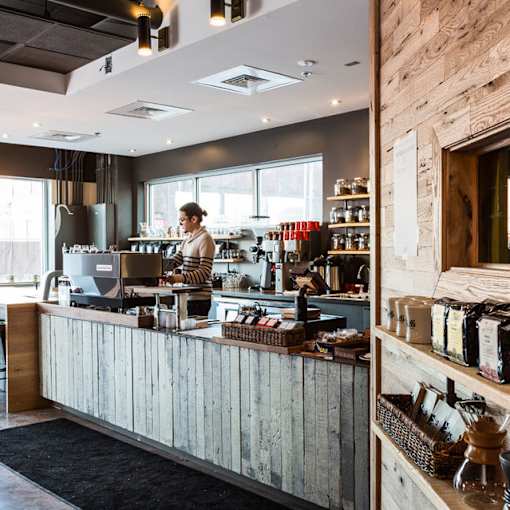 A person is standing behind a counter in a coffee shop.