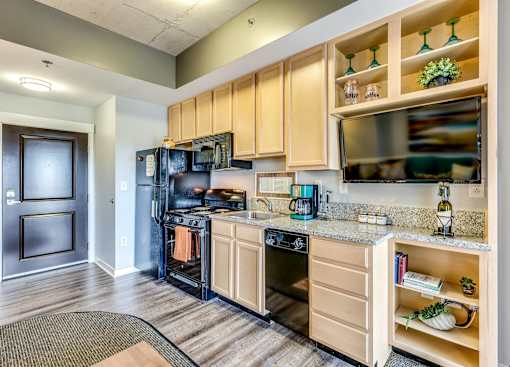 A kitchen with wooden cabinets and a black refrigerator.