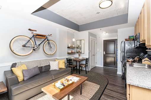 A modern living room with a grey couch and a bicycle on the wall.