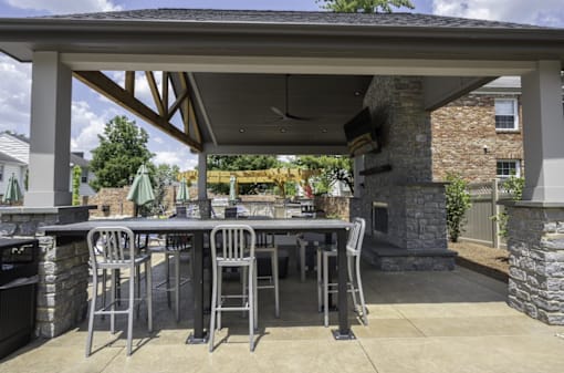 an outdoor kitchen with a bar and stools in front of a stone fireplace at Olde Towne in Kenwood, Ohio, 45243