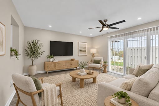 A living room with a flat screen TV, a sofa, a chair, a coffee table, and a potted plant.