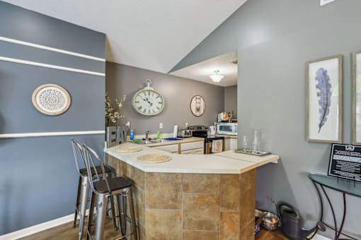 A kitchen with a bar area and a clock on the wall.