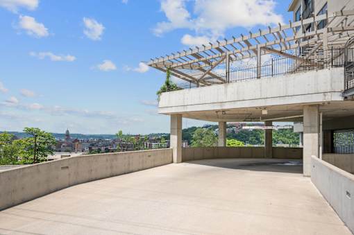A large, empty concrete patio with a pergola and a view of the city in the distance.