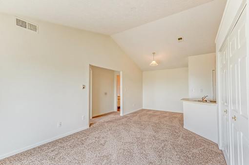 A large, empty room with a carpeted floor and white walls.