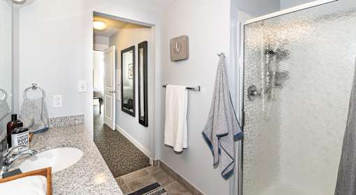 A bathroom with a sink, mirror, and shower.
