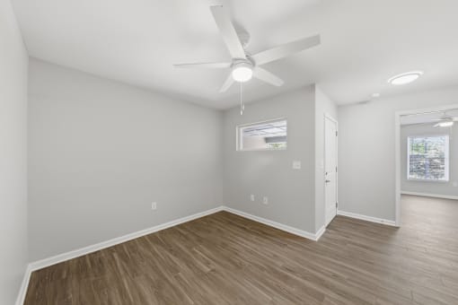 A room with a ceiling fan and wooden flooring.