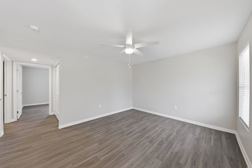 A room with a ceiling fan and light fixture, and a doorway leading to another room.