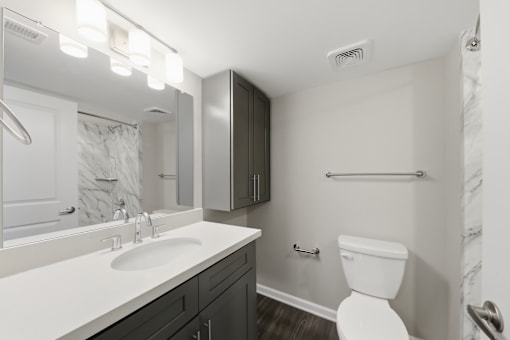 A white toilet sits in a bathroom next to a sink and a mirror.