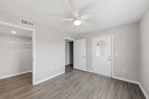 A room with a ceiling fan and a door leading to another room.
