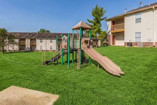 A playground with a green slide and a brown slide.