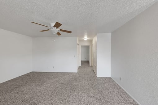 A room with a ceiling fan and carpeted floor.