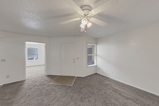 A room with a ceiling fan and carpeted floor.