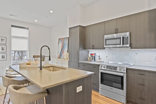 Kitchen with gray cabinets and a large island with a sink and two stools at Four23/Hoge, Cincinnati, OH